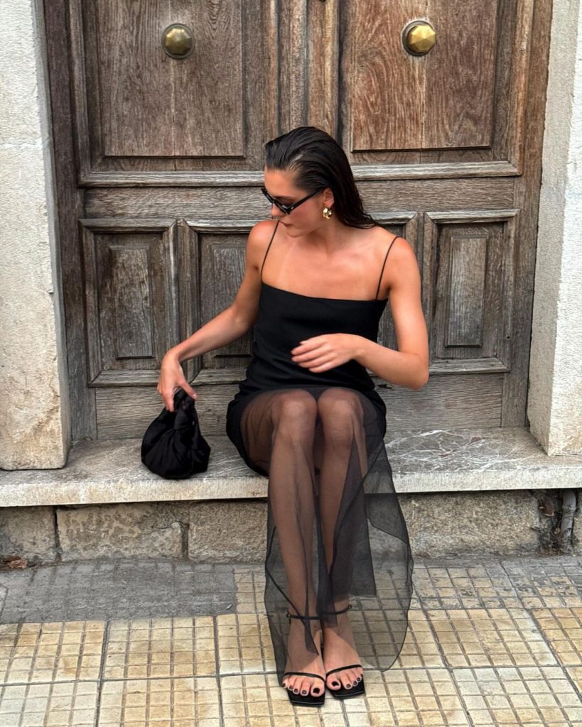 Valeria usando vestido preto de alça, bolsa preta e sandália de tiras preta kitten heels