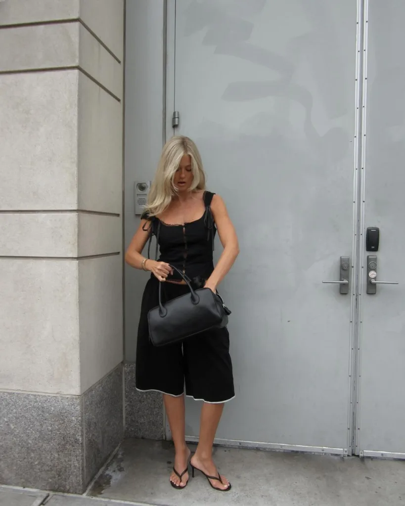 Josefine Haaning Jensen com blusa preta, bermuda de alfaiataria, bolsa preta e chinelo kitten heels preto