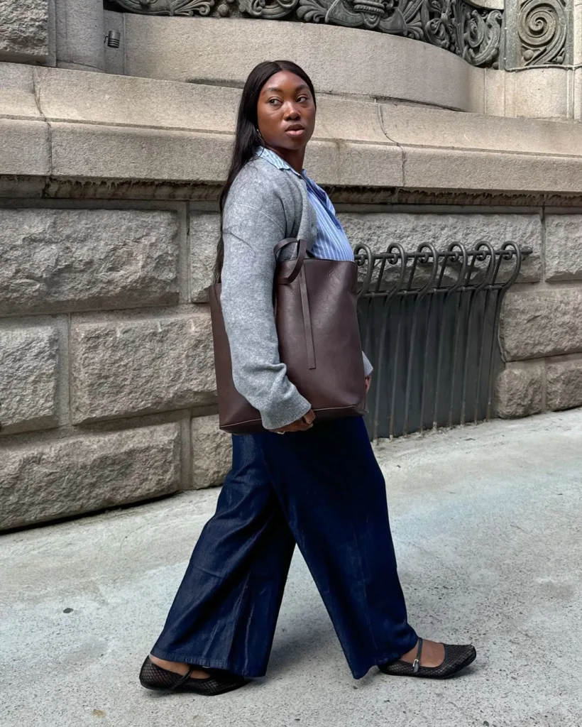 Nnenna com sapatilha preta, blazer cinza, bolsa marrom, calça azul-marinho