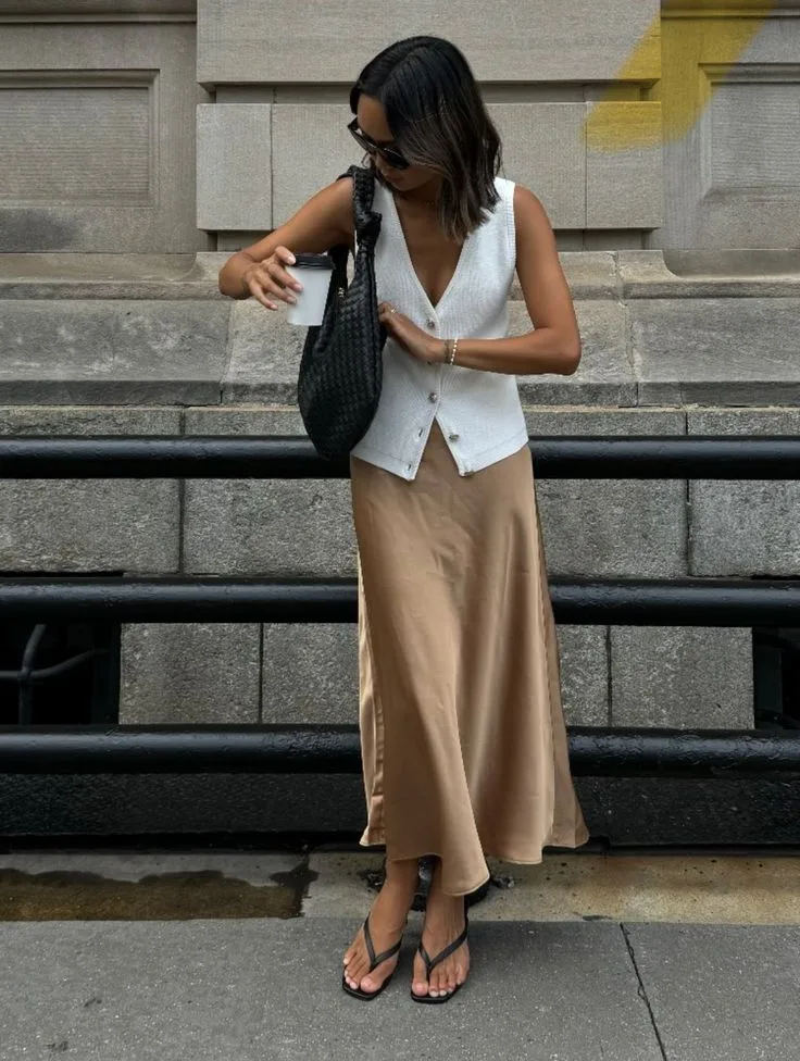 Mulher jovem com colete de alfaiataria, saia longa e chinelo kitten heels