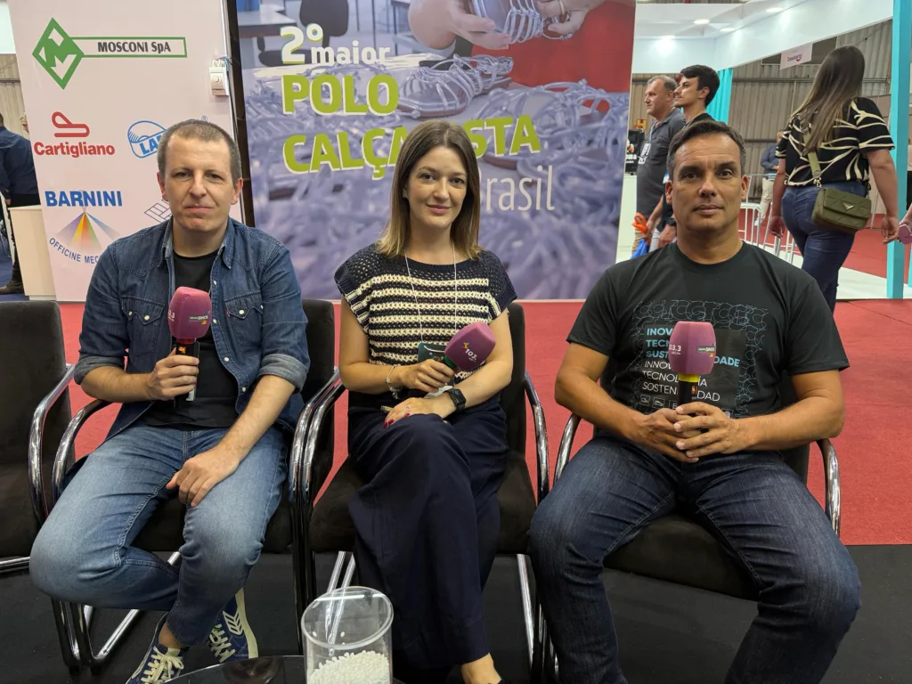 Dois homens e uma mulher sentados com microfones nas mãos