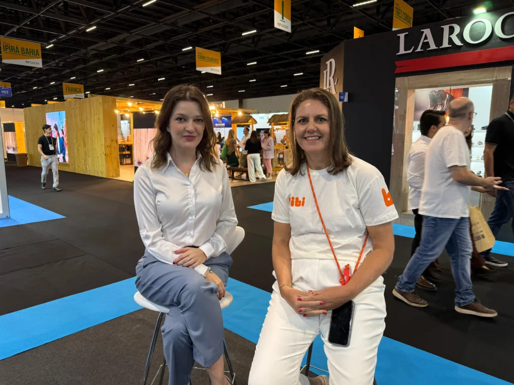 Duas mulheres vestidas de branco sentadas em banquinho