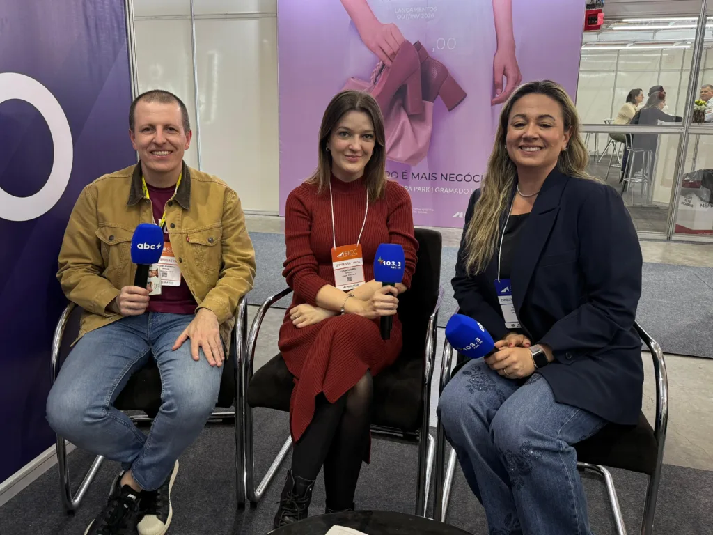Três pessoas sentadas com microfones nas mãos
