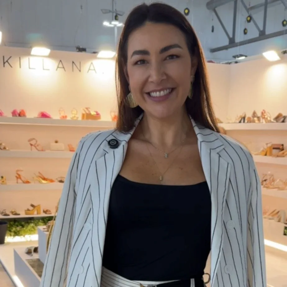 Mulher morena com blusa preta e blazer branco com listras pretas