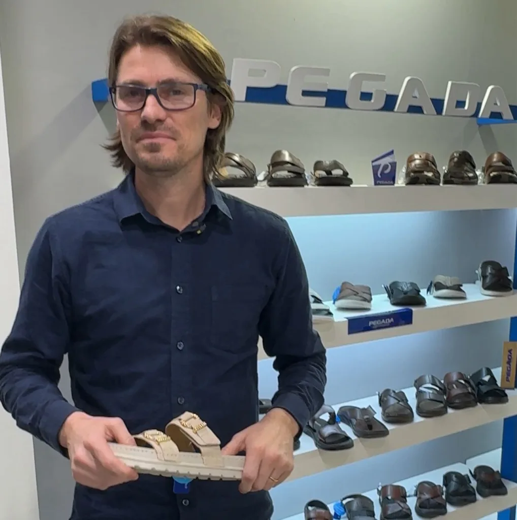 Homem vestido com camisa azul e sandália na mão